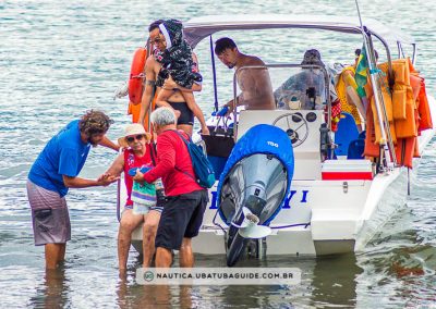 Senhora desembarcando com auxílio do Sylvio e do Daniel, pai e filho que comandam a operadora de turismo náutico Lucky Turismo