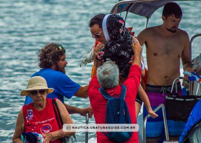 Sylvio, proprietário da operadora de turismo náutico Lucky Turismo dá suporte ao pai ao segurar criança pequena no desembarque