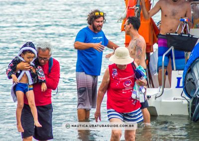 Sylvio, proprietário da Lucky Turismo, conduz criança pequena no colo até a areia durante desembarque