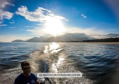 Sol caindo pela Serra do Mar ao fundo em um agradável passeio de lancha para a Ilha dos Porcos ao entardecer