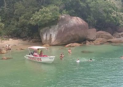 Pessoas mergulhando e nadando nas águas rasas da Praia da Barra e próximas da embarcação durante passeio de lancha com saídas da Praia da Fortaleza em Ubatuba