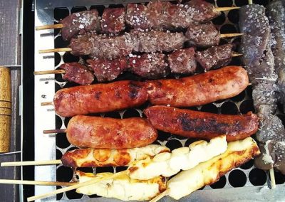 Espetos de churrasco assando na churrasqueira durante um passeio privativo, exclusividade e diferencial ao alugar a lancha da Sol e Sal Turismo Náutico