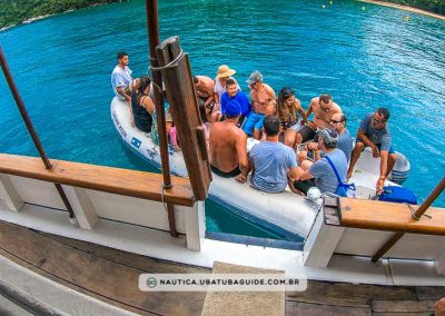 Pessoas a bordo do bote motorizado utilizado para embarque e desembarque dos passeios de escuna oferecidos pela Tubarão Turismo