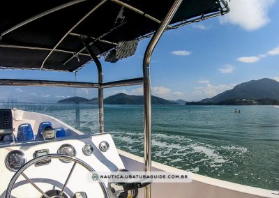 Praia ao fundo e painel de embarcação em primeiro plano. Lancha disponível para frete/aluguel e também para passeios de lancha coletivos em Ubatuba